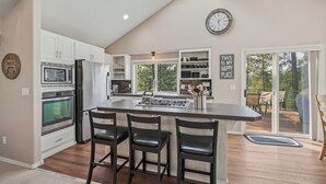 A kitchen with a central island, bar stools, a microwave, oven, and a refrigerator.