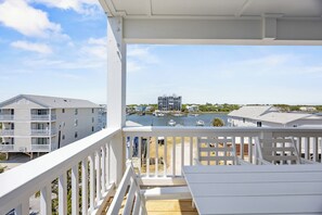 Ein Balkon mit Blick auf eine Marina, ein Gebäude gegenüber dem Wasser und ein klarer Himmel.