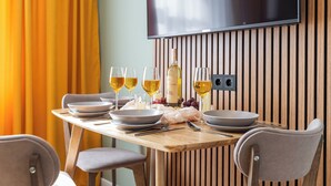 A dining table set with plates, glasses, and a bottle, with a TV mounted on the wall behind. - Apart in the historical center of Minsk (Minsk)