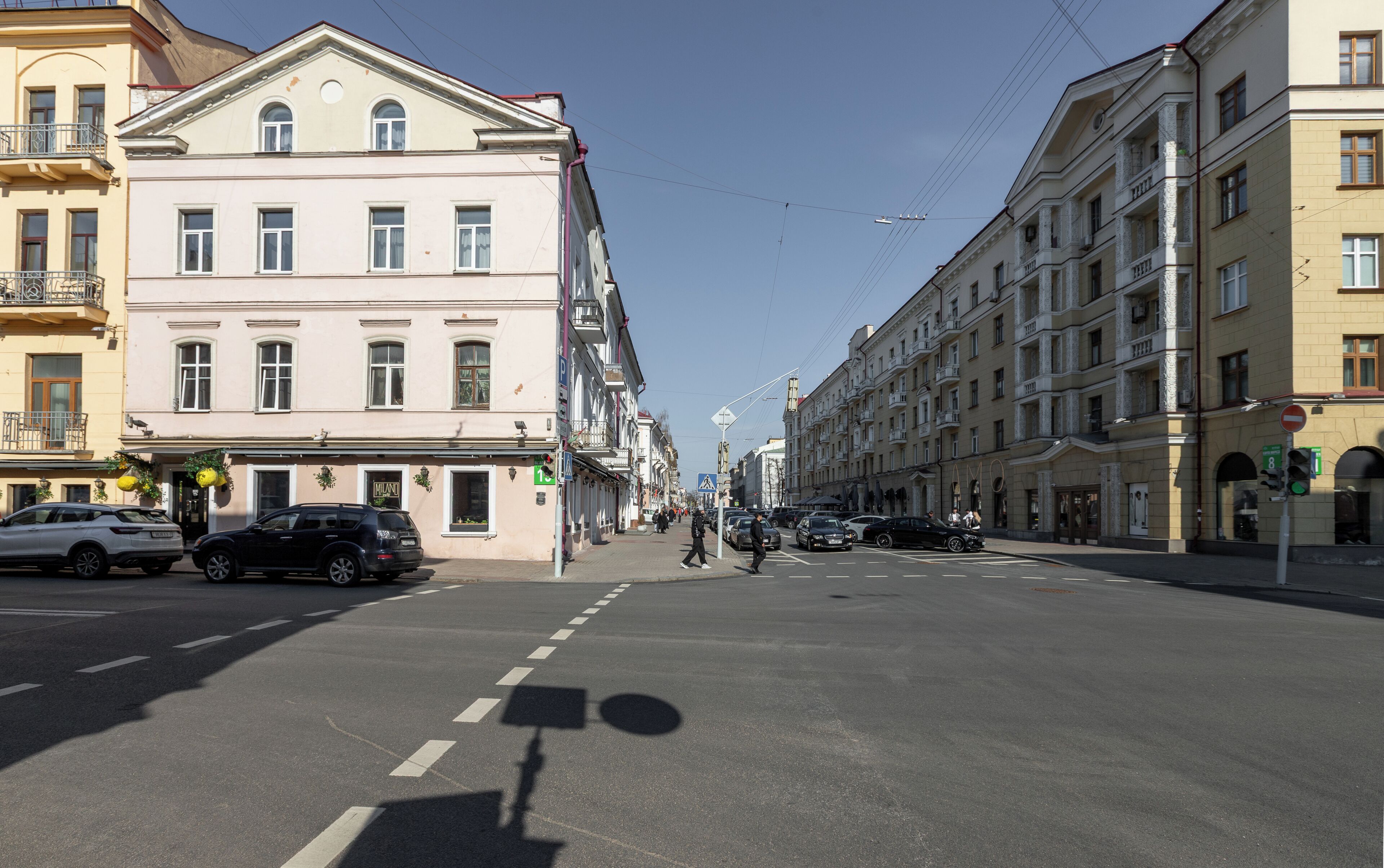 A street with buildings, cars, and a pedestrian crossing.