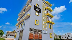 A multi-story building with balconies, a sign indicating it is a company service, and a gated entrance. - Deluxe Dholpanda Near Puri Lighthouse (Puri)