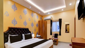 A hotel room with a large bed, a wooden wardrobe, a small table with a lamp, and a TV mounted on the wall. - Deluxe Dholpanda Near Puri Lighthouse (Puri)