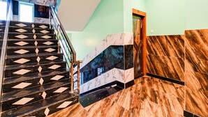 A staircase with a geometric pattern, a marble wall, and a wooden door. - Deluxe Dholpanda Near Puri Lighthouse (Puri)