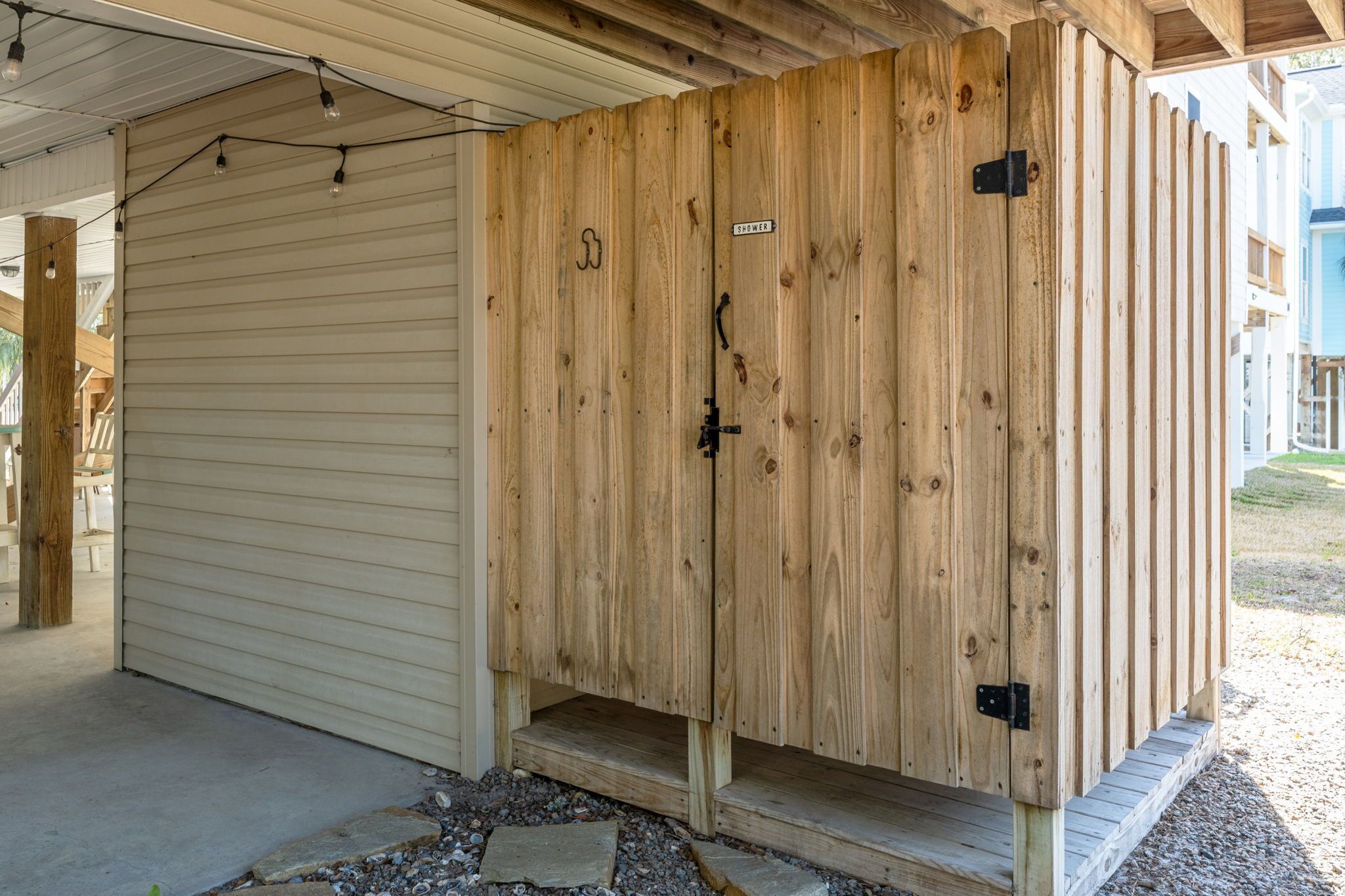 A wooden structure with a door labeled 'SHOWER' and a small step leading up to it.
