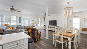 A spacious living area with a sofa, colorful armchair, dining table, and a chandelier. - Walk to Beach Arcade Games Family Friendly Oak Island (Oak Island)