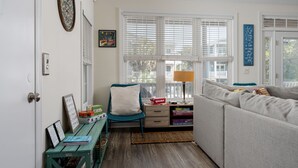 A room with a sofa, a chair, a desk, and a window with blinds. - Walk to Beach Arcade Games Family Friendly Oak Island (Oak Island)