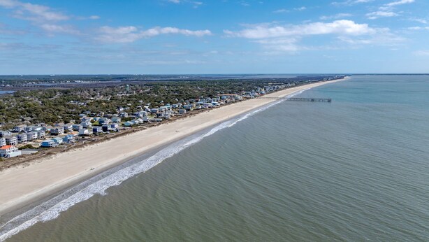 A coastal area with a long beach, a pier extending into the water, and a dense cluster of buildings along the shore. - Walk to Beach Arcade Games Family Friendly Oak Island (Oak Island)