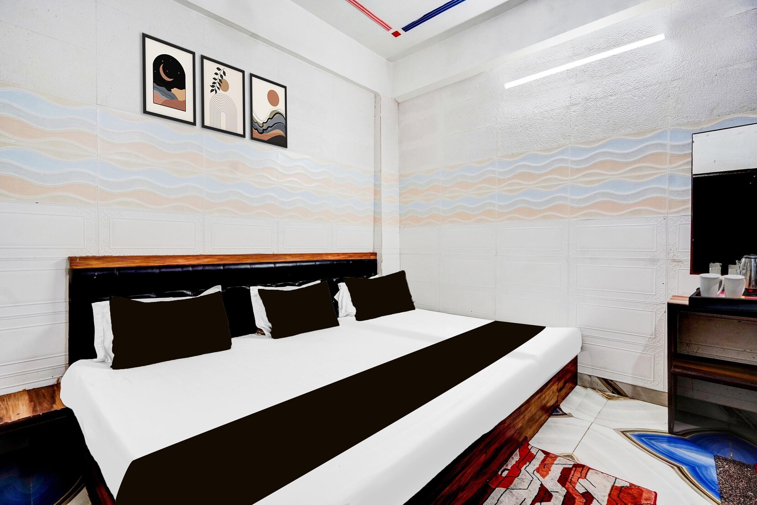 A hotel room with a bed, a nightstand, a mirror, and artwork on the wall.
