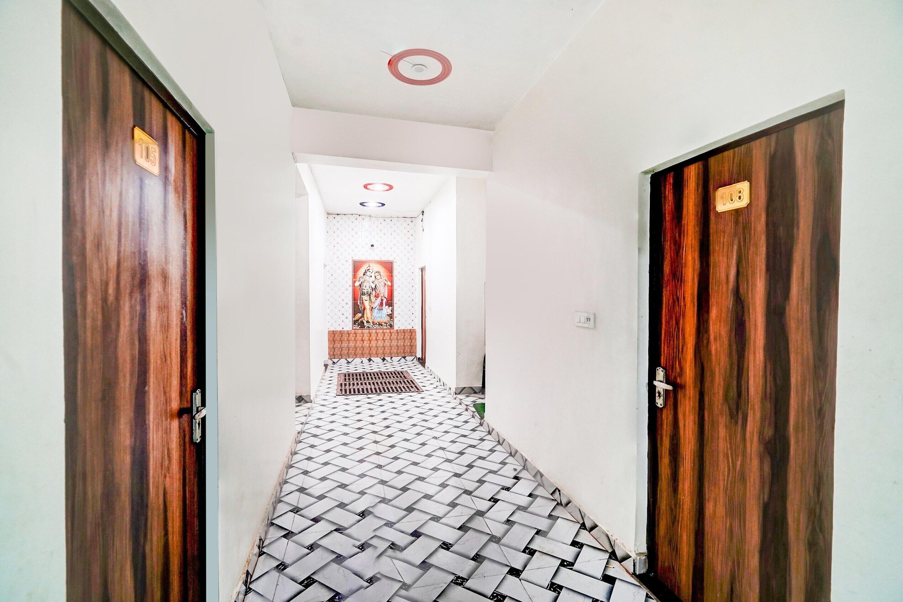 A hallway with patterned flooring, wooden doors, and a ceiling light fixture.