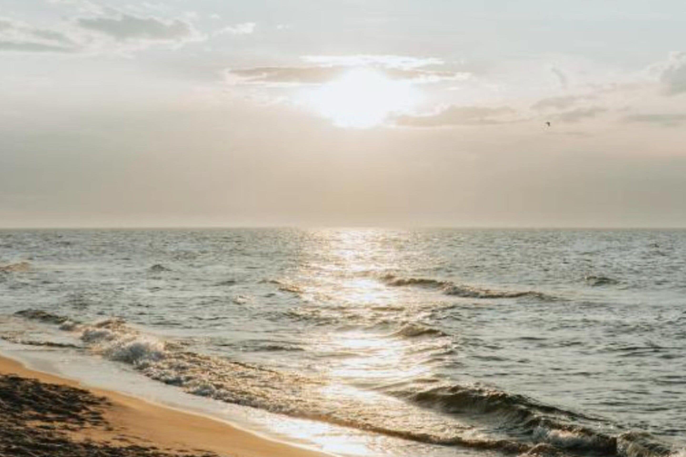 A beach with waves and a clear sky.