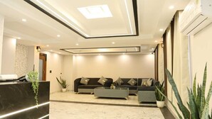 Una hall moderna con una reception, una zona salotto e una pianta grande.