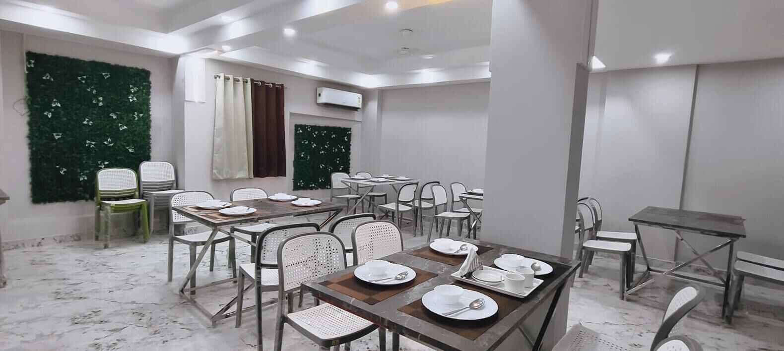 A conference room with tables set for a meeting, white chairs, and a green wall decoration.