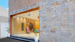 Une entrée moderne avec une porte en verre, un mur en pierre et un espace détente à l’intérieur.
