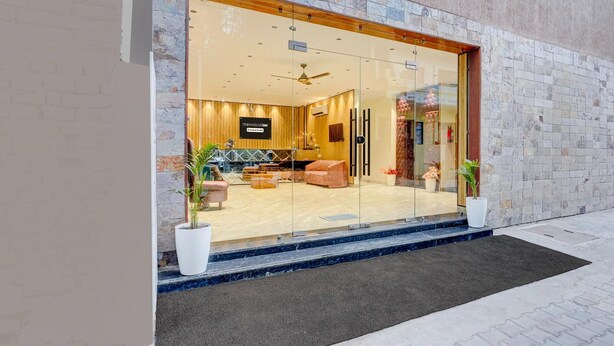 Une entrée d’hôtel moderne avec une façade en verre, un espace d’accueil et un coin salon visible à l’intérieur.