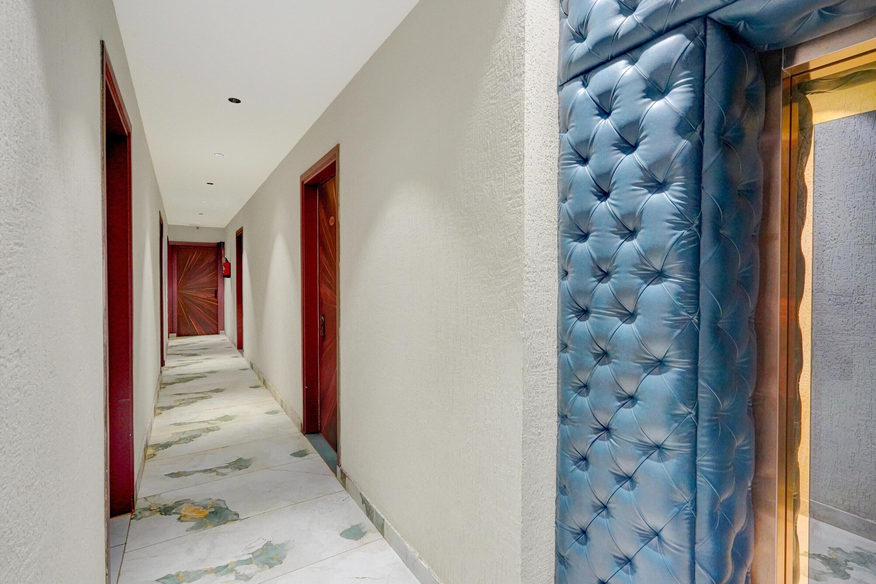 Un pasillo con piso estampado, puertas de madera y un cabecero tapizado en azul.