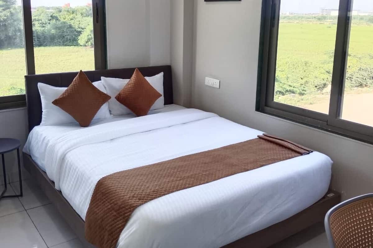 A hotel room with a large bed, a view of the outdoors, and a painting on the wall.