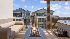Eine Dachterrasse mit Feuerstelle, Sitzgelegenheiten im Freien und Blick auf Wohnhäuser.