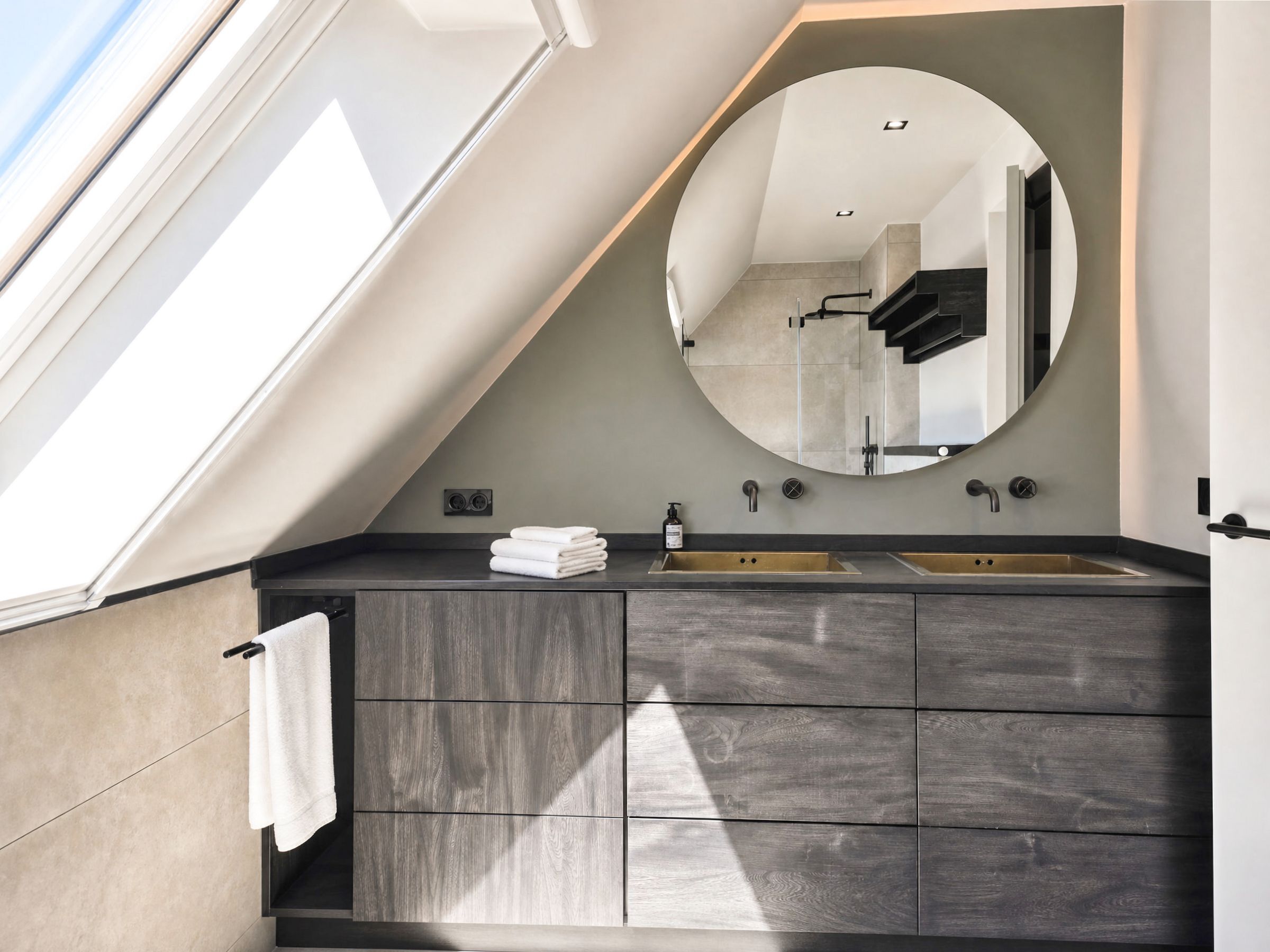 A modern bathroom with a skylight, a large mirror, and a dual sink vanity.