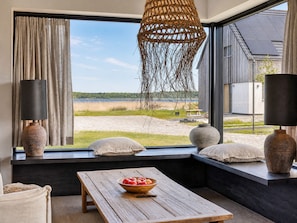 Ein Zimmer mit großem Fenster, einem Holztisch mit Obstschale und zwei Lampen.
