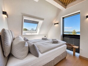 Ein Schlafzimmer mit Dachfenster, einem großen Fenster mit Blick und einer hölzernen Bank.