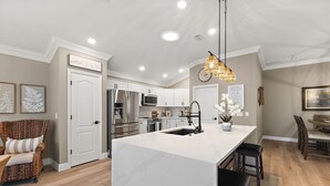 A modern kitchen with white cabinetry, stainless steel appliances, and a large island. - Charming 3-bedroom house in the heart The Villages (The Villages)