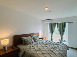Ein Schlafzimmer mit einem Bett, Nachttischen, einer Lampe und einem Fenster mit Vorhängen.