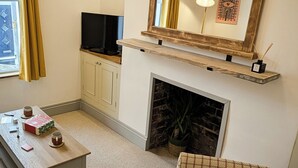 Ein Wohnzimmer mit Kamin, Fernseher, Sofa und Couchtisch.