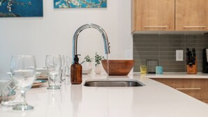 A modern kitchen with a stainless steel sink, a wooden bowl, and a bottle of hand soap. - Riviere Apartments King Bed Suite & Pool & Gym & Pet Friendly & Near Epic Universe (Orlando)