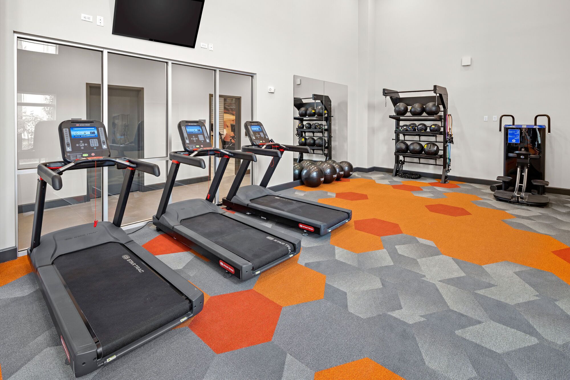 A gym with treadmills, a weight rack, and exercise balls.