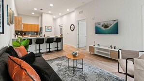 A modern living room with a sofa, coffee table, and a TV mounted on the wall. - Riviere Apartments King Bed Suite & Pool & Gym & Pet Friendly & Near Epic Universe (Orlando)