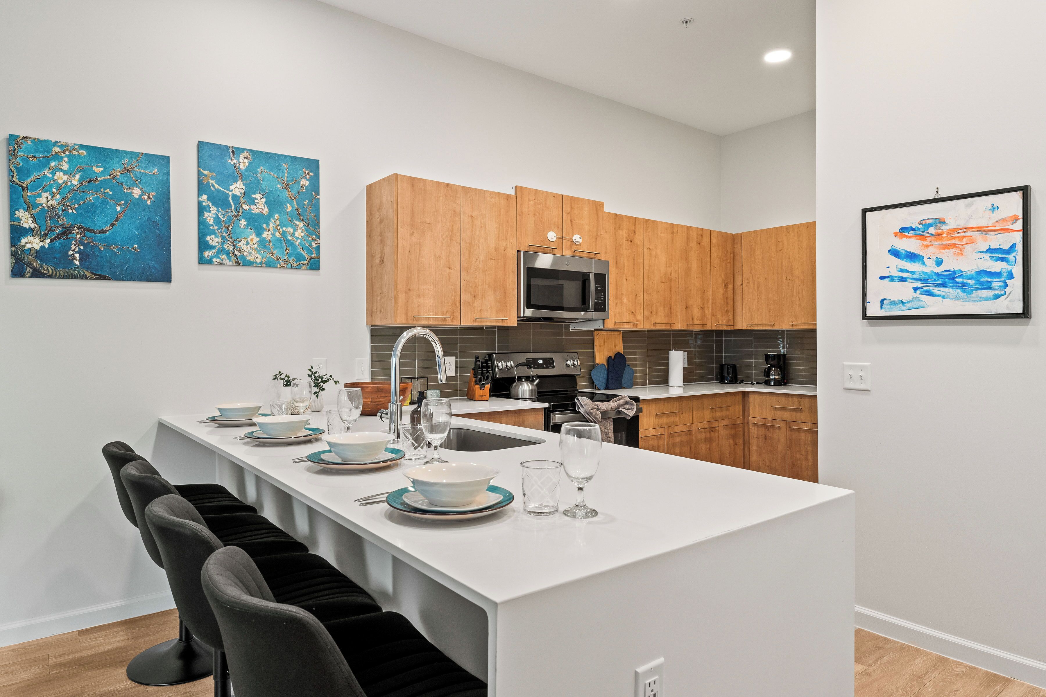 A modern kitchen with wooden cabinets, a central island, and a microwave.