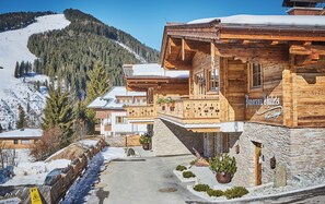 A wooden chalet with stone walls, a balcony, and a sign reading 'Panorama Chalet.' - Panorama Chalets by we rent (Saalbach)