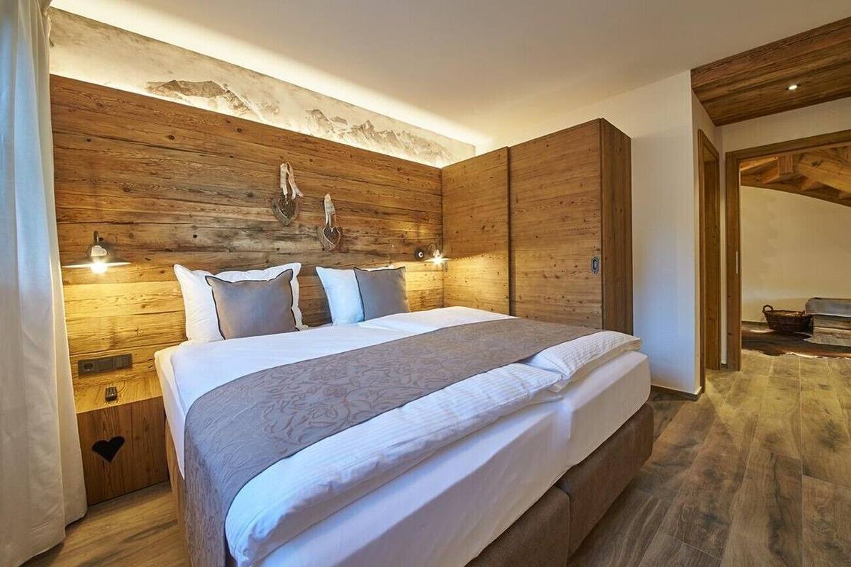 A bedroom with a wooden headboard, a bed with white linens, two bedside lamps, and a wooden nightstand.