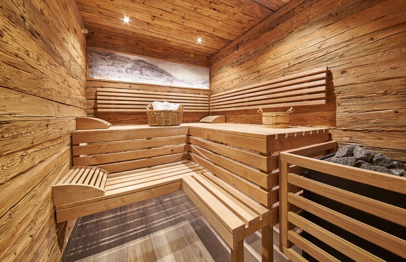 Una sauna de madera con bancos, un banco de madera, una cesta y un balde.