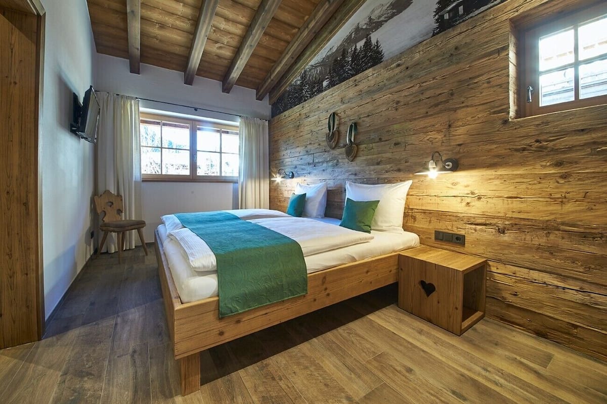 A wooden cabin-style bedroom with a bed, bedside table, and a window.