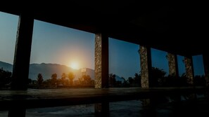 Una estructura con columnas y vistas al atardecer sobre montañas.