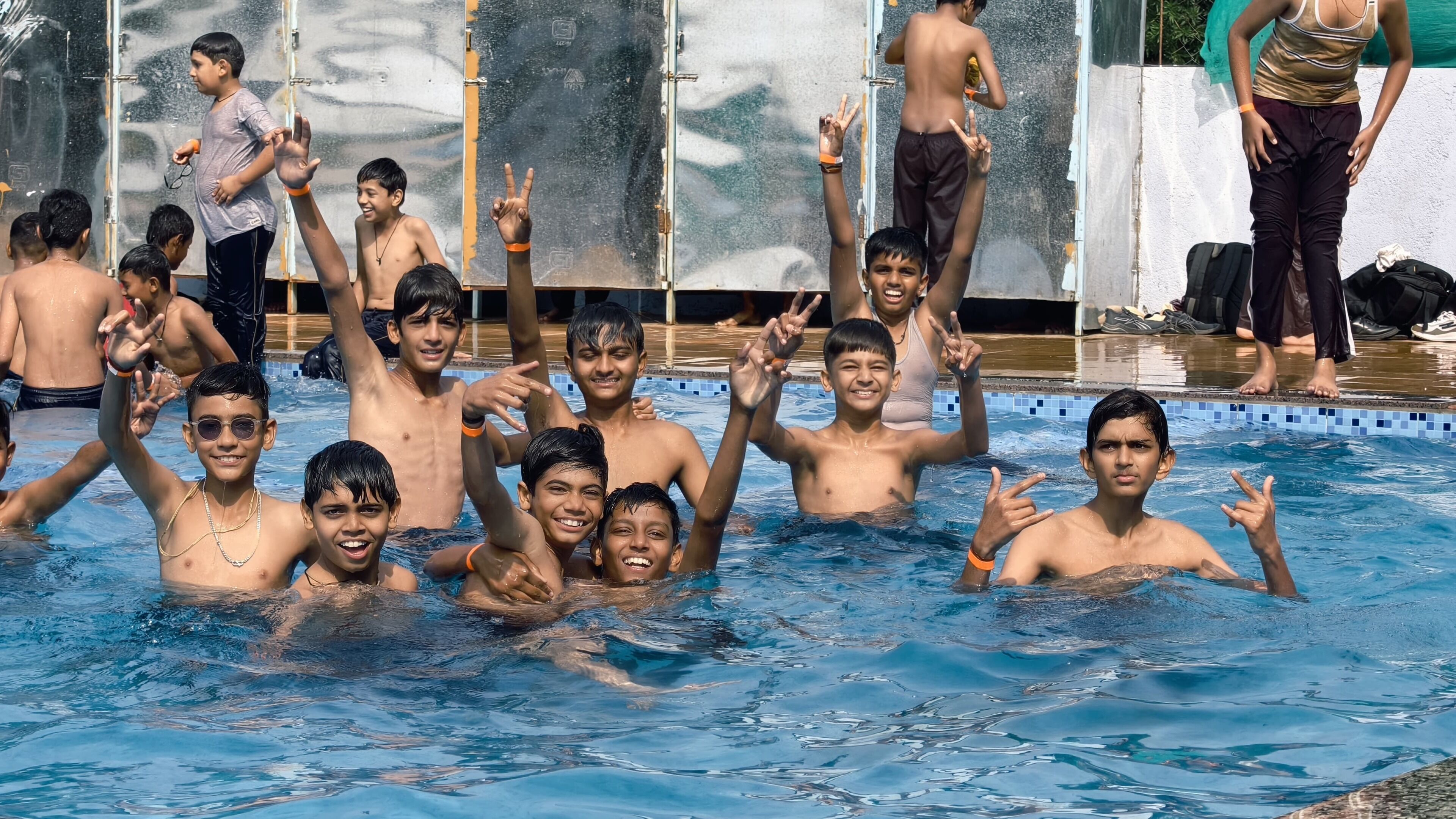 A swimming pool with children playing and making hand gestures.