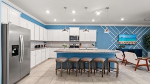 A modern kitchen with a central island, bar stools, white cabinets, and pendant lighting. - Upstay Disney Family Adventure With Pool Hot Tub (Davenport)