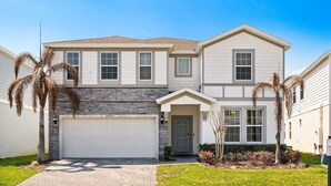 A two-story house with a garage, a front door, and a small front yard with palm trees. - Upstay Disney Family Adventure With Pool Hot Tub (Davenport)