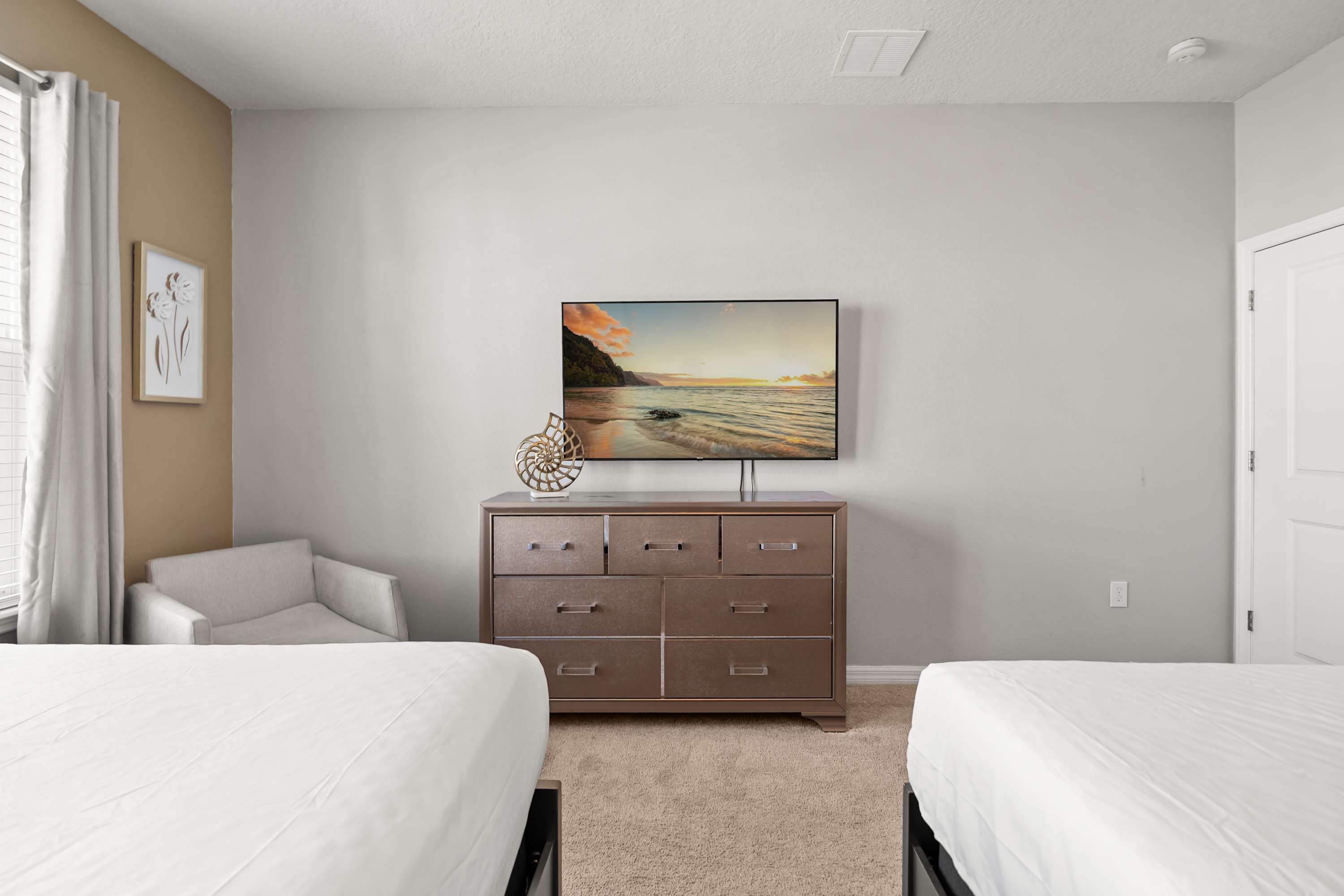 A bedroom with two beds, a dresser, a painting, and a chair.