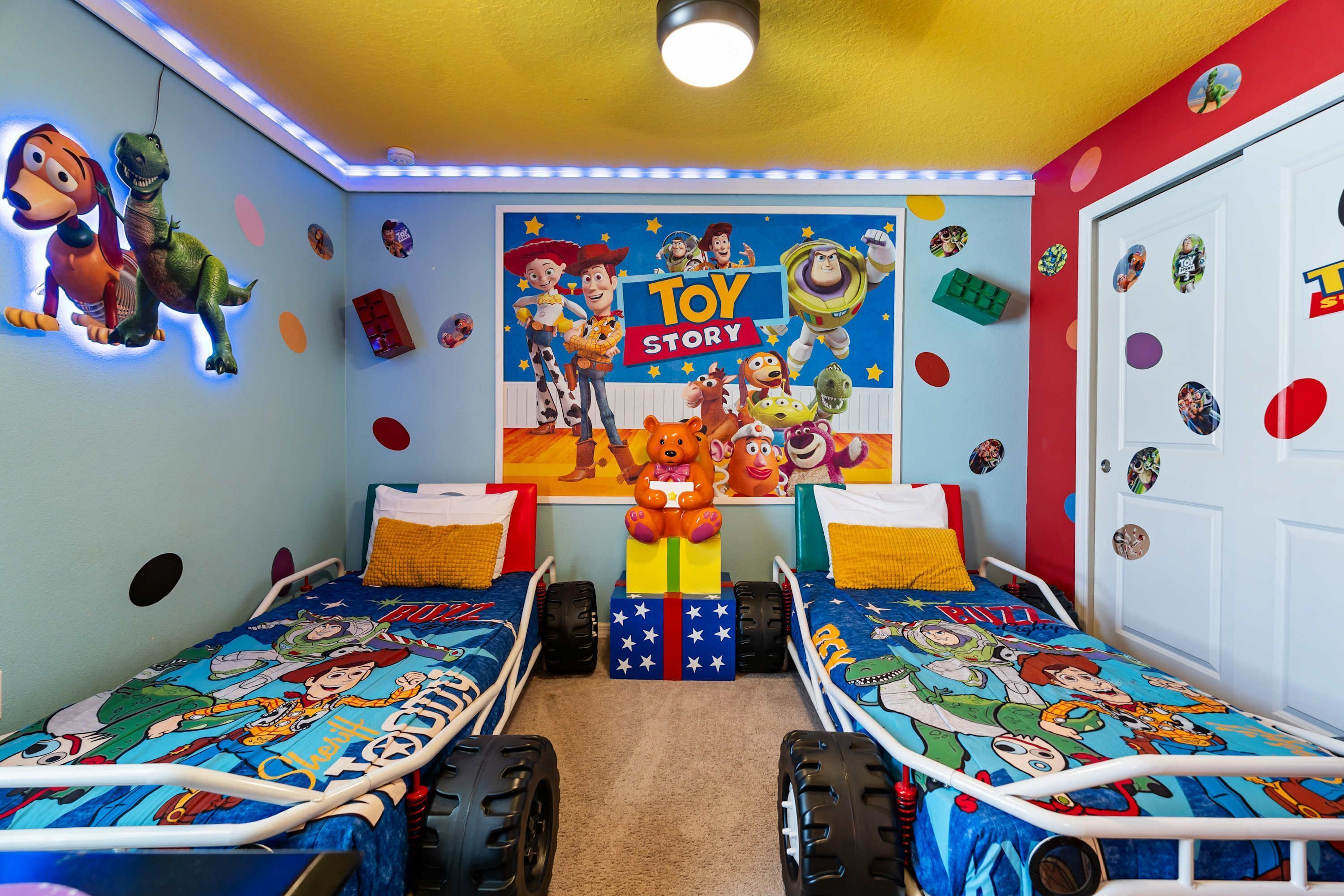 Habitación infantil con dos camas, un mural de Toy Story y diversos juguetes y adornos.