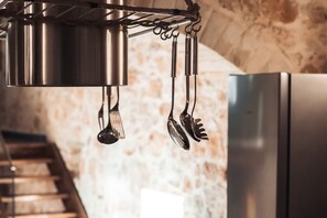 Una cucina con pentole e utensili appesi, un frigorifero in acciaio inossidabile e una scala.