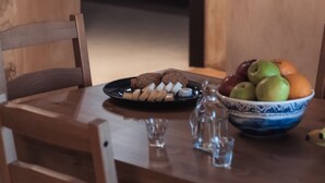 A wooden dining table with a plate of snacks, a bowl of fruit, and two glasses. - Vertigo Stone Villa - Roumeli Private Pool Escape (Mylopotamos)