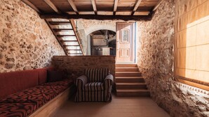 A narrow stone-walled corridor with a wooden staircase, a bench, and a striped chair. - Vertigo Stone Villa - Roumeli Private Pool Escape (Mylopotamos)