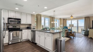A modern kitchen with white cabinetry, stainless steel appliances, and a central island. - Gulf-Front Corner Unit with Stunning Panoramic Views (Panama City Beach)