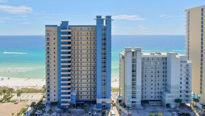 A high-rise hotel with multiple floors, a beach view, and a parking area. - Gulf-Front Corner Unit with Stunning Panoramic Views (Panama City Beach)