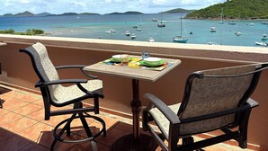 A terrace with two chairs and a table, overlooking a marina with boats and a hilly landscape. - Stunning Penthouse at Grande Bay - Breathtaking Views and Luxury Living! (St John)