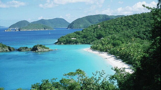 A coastal landscape with a beach, clear blue waters, and lush green hills in the background. - Stunning Penthouse at Grande Bay - Breathtaking Views and Luxury Living! (St John)