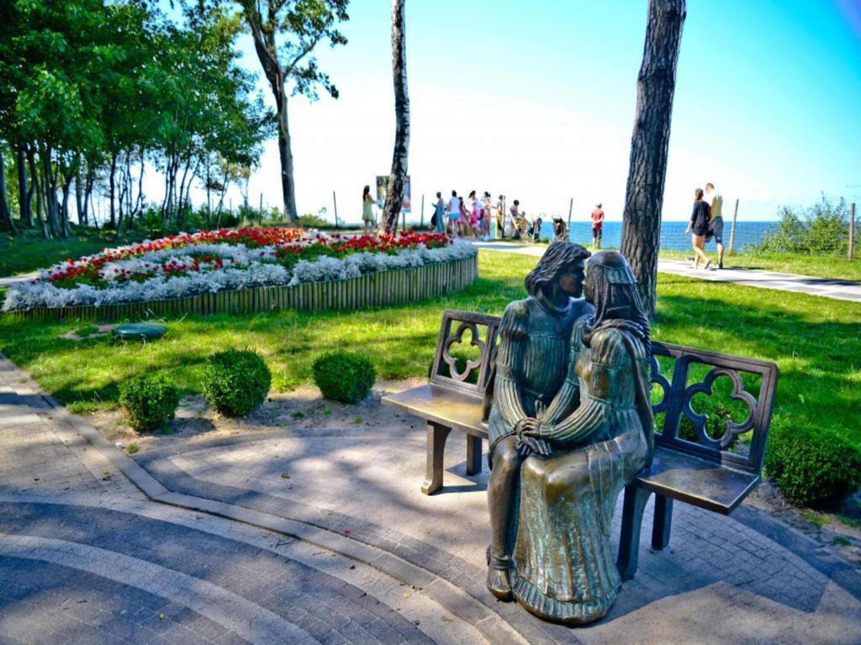 A park with a bench featuring a sculpture of two figures.