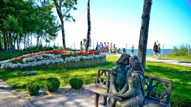 Un parque con un banco que presenta una escultura de dos figuras.